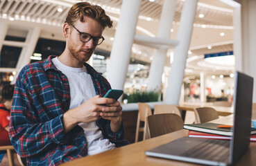 Young caucasian guy using smartphone at table