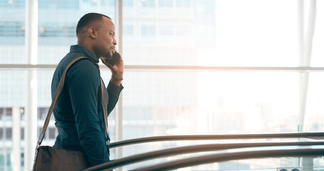 On call and on the move. Cropped shot of a handsome young businessman taking a phonecall while going up an escalator in a modern workplace.