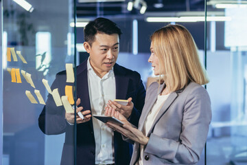 Team of business workers develop a business strategy, and develop a plan, an Asian man smiles at a female companion