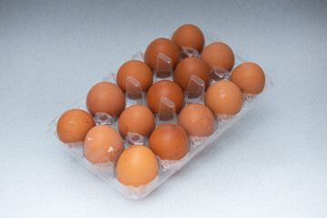tray with 15 brown eggs on a white-grey gradient background