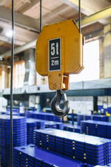 A large warehouse of metal plates lying on pallets. Crane in the foreground