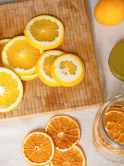 Sliced dried round pieces of oranges on a wooden board surrounded by fresh fruit, top view. Space for text.