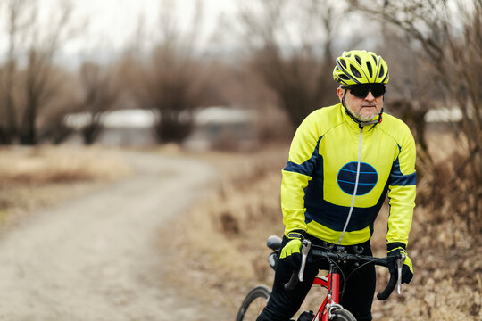 A senior male bicyclist taking a break in nature on a bike.