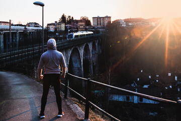 Man with hood watches the sunset.