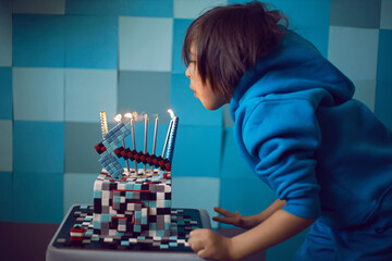 boy in blue clothes looks at cake pixels with a pickaxe and candles and lights in the studio....