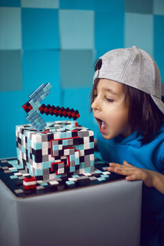 boy in blue clothes bites at cake pixels with a pickaxe in the studio. birthday five years