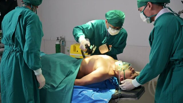 Team of doctor helping by AED defibrillation with accident injured patient unresponsive in emergency room