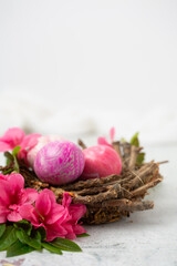 Easter Eggs Dyed with Various Patterns of Pink Silk Surrounded by Pink Azaleas on a White Background