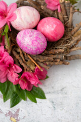 Obraz na płótnie Canvas Easter Eggs Dyed with Various Patterns of Pink Silk Surrounded by Pink Azaleas on a White Background