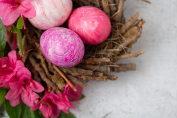 Obraz na płótnie Canvas Easter Eggs Dyed with Various Patterns of Pink Silk Surrounded by Pink Azaleas on a White Background