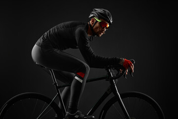 male cyclist riding road bicycle on black background