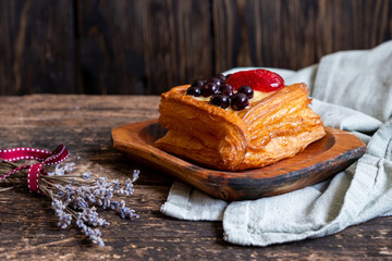 Pastry with blaackberries, starwberry on a wooden plate near tied lavender with a red ribbon and a light green material