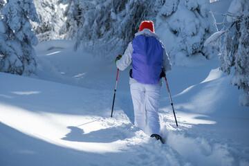 Footage of the back of a young hiker with a white ski costume and a bright colorful hat