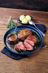 Traditionell gegrilltes Gourmet Entenbrust Filet mit Haut serviert mit Kartoffelknödel in Dunkelbier Sauce als close-up auf einem rustikalen Metall Tablett