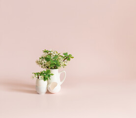 Cherry blossom spring bouquet in a jug and egg on pink background. Easter greeting card with copy space. Spring flowers minimal background.