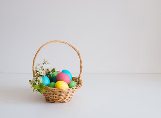 Easter basket with eggs on a white background. Beautiful Easter composition with spring flowers. Copy space.
