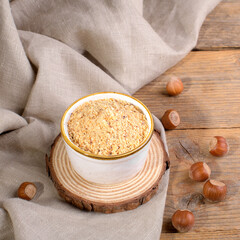 Raw Organic Ground Hazelnut Flour in a Bowl with whole nuts on rustic wooden background. Alternative nut flour for keto diet and gluten free food. Paleo and ketogenic diet baking cooking concept