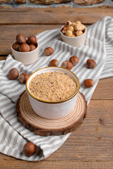 Raw Organic Ground Hazelnut Flour in a Bowl with whole nuts on rustic wooden background. Alternative nut flour for keto diet and gluten free food. Paleo and ketogenic diet baking cooking concept