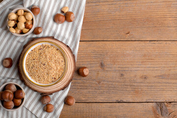Raw Organic Ground Hazelnut Flour in a Bowl with whole nuts on rustic wooden background. Alternative nut flour for keto diet and gluten free food. Paleo and ketogenic diet baking cooking concept above