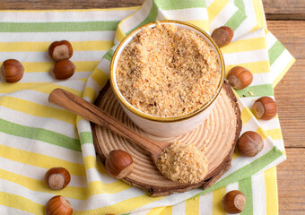 Raw Organic Ground Hazelnut Flour in a Bowl with whole nuts on rustic wooden background....