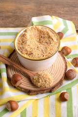Raw Organic Ground Hazelnut Flour in a Bowl with whole nuts on rustic wooden background. Alternative nut flour for keto diet and gluten free food. Paleo and ketogenic diet baking cooking concept above