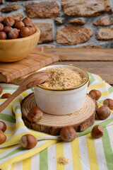 Raw Organic Ground Hazelnut Flour in a Bowl with whole nuts on rustic wooden background. Alternative nut flour for keto diet and gluten free food. Paleo and ketogenic diet baking cooking concept