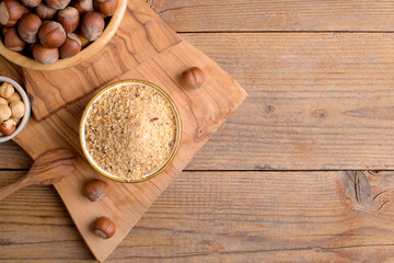 Raw Organic Ground Hazelnut Flour in a Bowl with whole nuts on rustic wooden background. Alternative nut flour for keto diet and gluten free food. Paleo and ketogenic diet baking cooking concept above