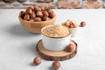 Raw Organic Ground Hazelnut Flour in a Bowl with whole nuts on grey stone background. Alternative nut flour for keto diet and gluten free food. Paleo and ketogenic diet baking cooking concept