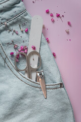 manicure set in a pocket of light jeans on a pink plain background with pink gypsophila