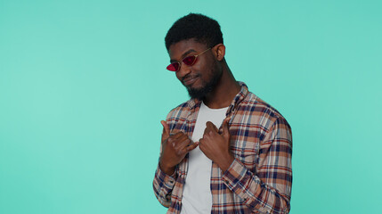 Cheerful happy african american young guy in shirt listening music dancing disco fooling around having fun expressive gesticulating hands. Adult man posing isolated on blue studio wall background