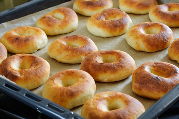 Homemade round buns on a baking sheet. View from a high angle. Selective focus with blurred background, natural light