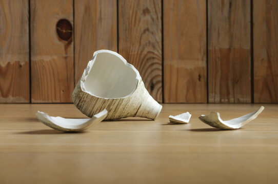 A broken vase with fragments, against the background of a wall of wooden planks. Selective focus on a vase, with blurred background and foreground