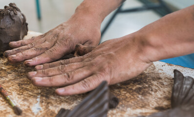 Artisan making a clay figure of a fish, his hands are distinguished creating details such as his scales, allowing us to see his mastery in handling the material.