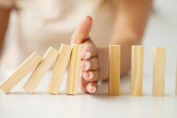 Hand of woman stopping and protect wooden block falling