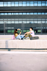 Teenage couple sitting on railroad station and taking photos.