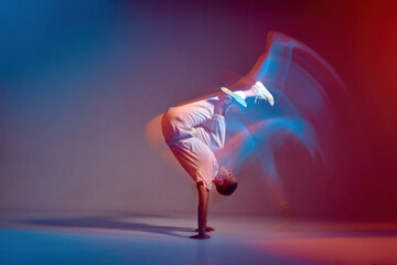 Young girl dancing contemporary dance in neon studio light. Acrobatic dancer. Breakdance school ad. Long exposure