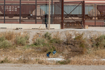 Two men hide in the bushes to avoid being caught by immigration agents at the US-Mexico border in Ciudad Juarez Chihuahua Mexico.