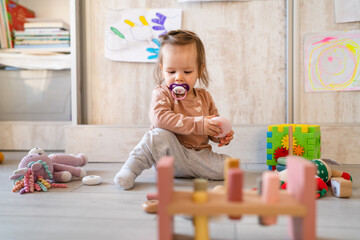 One baby small caucasian infant girl playing on the floor at home copy space