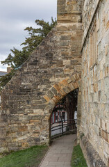 Archway with black railing running alongside a castle wall