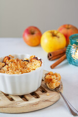 Apples under the crumble. Baked apples with crumble. Autumn dessert. Apples with cinnamon. Autumn fruits. Apples and a candle in the background. Cinnamon sticks.