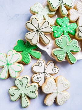 Various Shamrock Sugar Cookie Designs Scattered On A Platter With A Marble Background