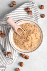 Raw Organic Ground Hazelnut Flour in a Bowl with whole nuts on grey stone background. Alternative nut flour for keto diet and gluten free food. Paleo and ketogenic diet baking cooking concept above