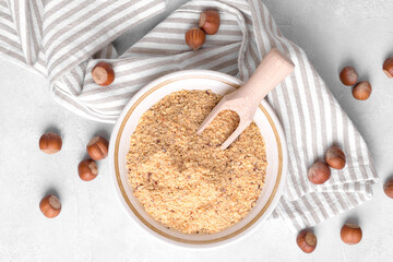 Raw Organic Ground Hazelnut Flour in a Bowl with whole nuts on grey stone background. Alternative...