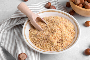 Raw Organic Ground Hazelnut Flour in a Bowl with whole nuts on grey stone background. Alternative nut flour for keto diet and gluten free food. Paleo and ketogenic diet baking cooking concept