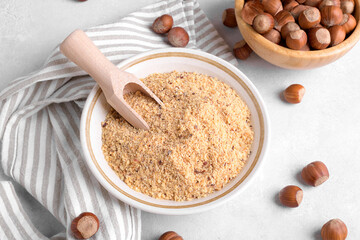 Raw Organic Ground Hazelnut Flour in a Bowl with whole nuts on grey stone background. Alternative nut flour for keto diet and gluten free food. Paleo and ketogenic diet baking cooking concept