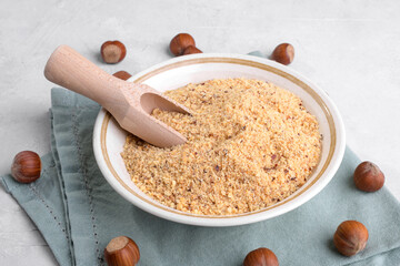 Raw Organic Ground Hazelnut Flour in a Bowl with whole nuts on grey stone background. Alternative nut flour for keto diet and gluten free food. Paleo and ketogenic diet baking cooking concept