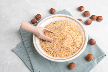 Raw Organic Ground Hazelnut Flour in a Bowl with whole nuts on grey stone background. Alternative nut flour