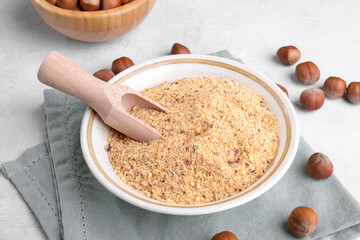 Raw Organic Ground Hazelnut Flour in a Bowl with whole nuts on grey stone background. Alternative nut flour for keto diet and gluten free food. Paleo and ketogenic diet baking cooking concept