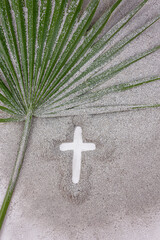 Christian Cross drawing in ash with palm leaf. Concept for Lent Season, Holy Week, Palm Sunday and...