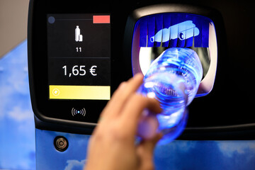 man inserting a plastic bottle into a plastic bottle recycling machine, backup of plastic bottles in the vending machine - obrazy, fototapety, plakaty